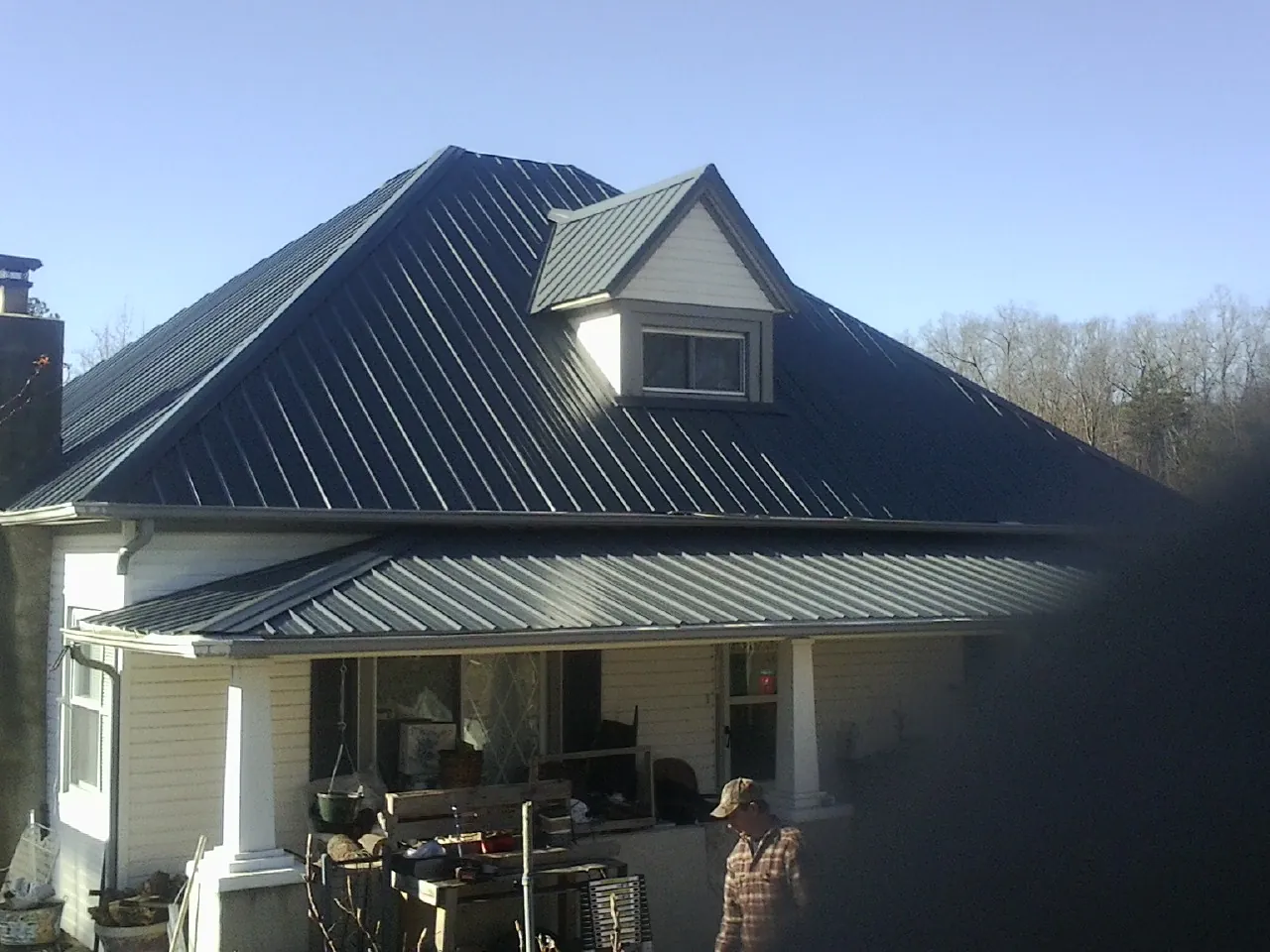 Dark blue standing seam metal roof with a dormer above a front porch in Plymouth